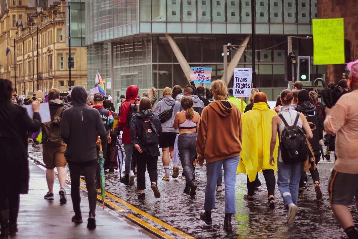 A diverse group of people walking together on a campus path, some wearing colored beads, showing community support and s