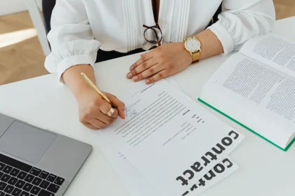 Hands holding contract documents with budget papers and calculator on desk