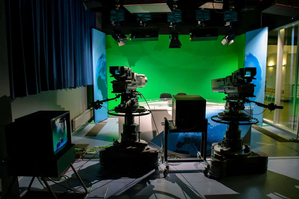Nachrichtenstudio mit Moderator vor Kamera und Schlagzeilen-Display