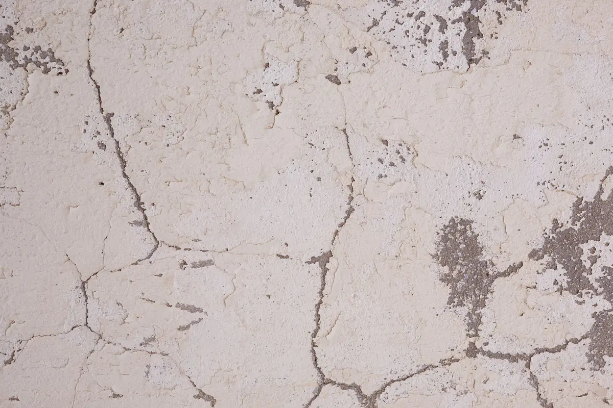 Visible cracking and deterioration along the edge of a damaged reflecting pool with stone paving