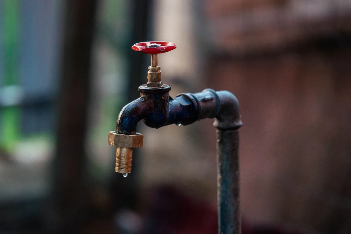Equipo de reparación trabajando en tuberías de agua bajo tierra en una calle residencial
