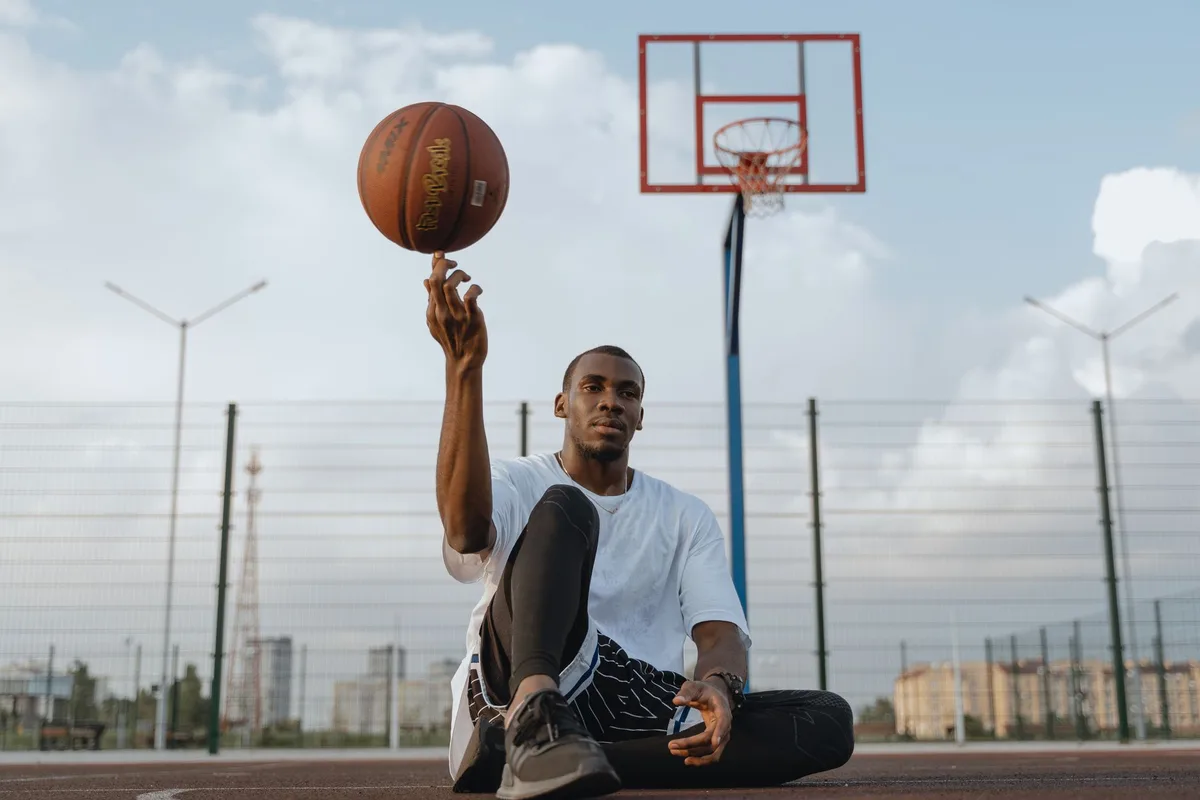 Basketbalista w akcji podczas gry przygotowawczej, rzucający piłkę na tle hali sportowej
