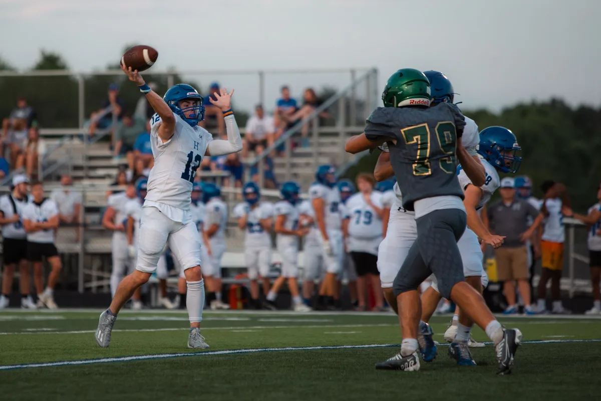 Quarterback releasing pass during high school football game with emerging role