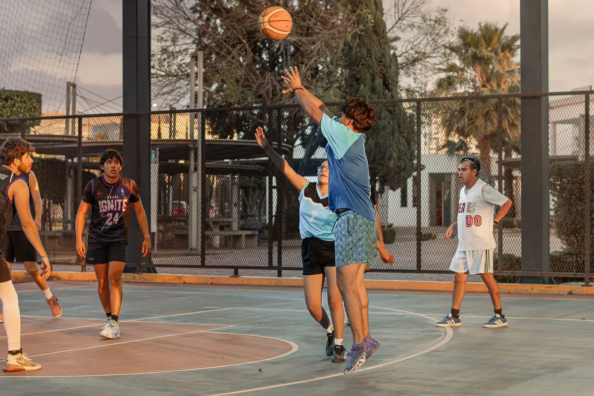 Basketball coach on sideline during a game, gesturing to players on the court