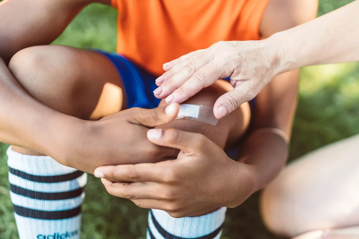 Adult hands rinsing a child's hand under cool running water for burn first aid