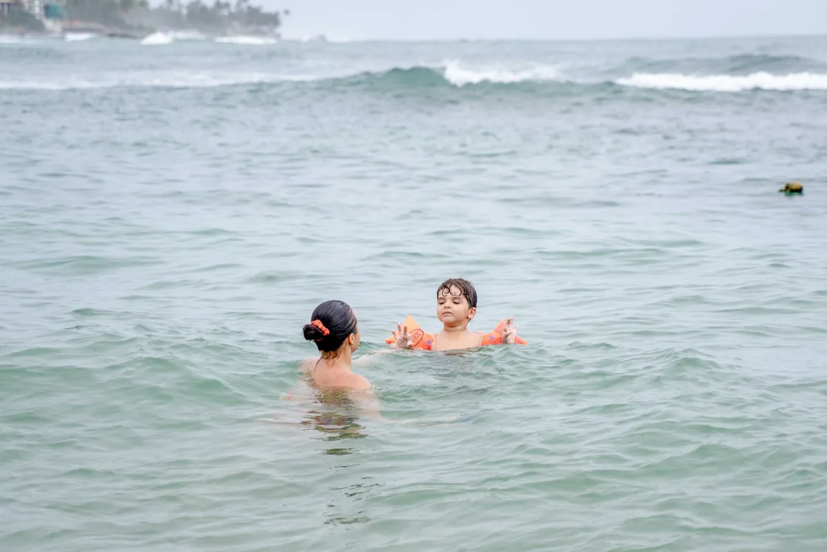 Ein Kind tr&auml;gt eine Schwimmweste und wird von einem Erwachsenen beaufsichtigt.