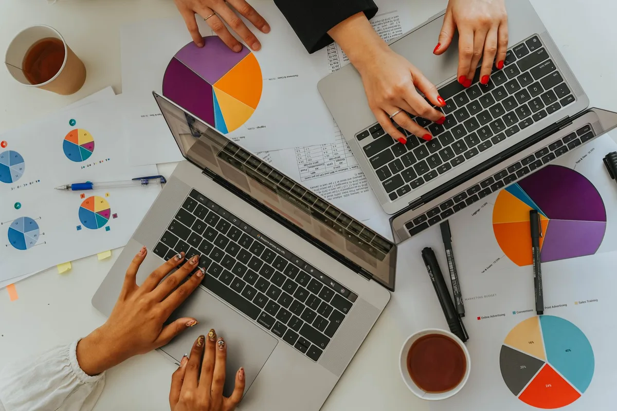 Person reviewing business rankings and state economic data at a desk with charts and reports