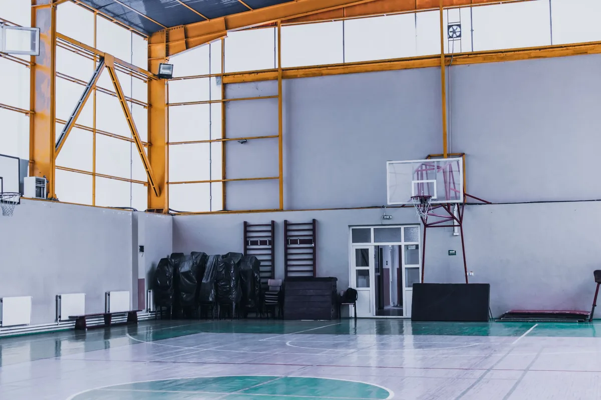 Coach's equipment on a gymnasium bench with empty court in background
