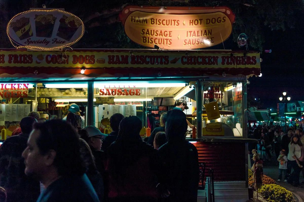 Skaters and pedestrians share a closed street lined with vendor booths and live music during an urban street festival.
