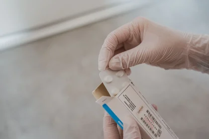 Hands holding a medication bottle at a mailbox, representing mail delivery of prescription drugs