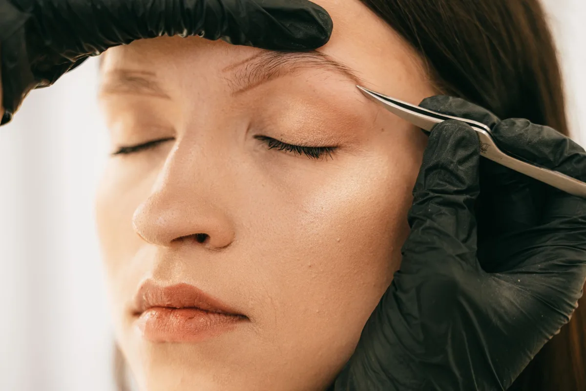 Fine-tipped tweezers being used to safely remove a tick from skin.