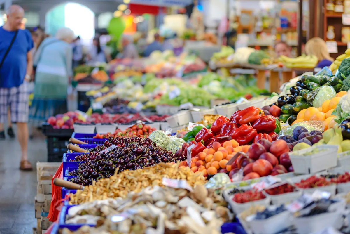 Customers browsing fresh produce at a community farmers market on a sunny day