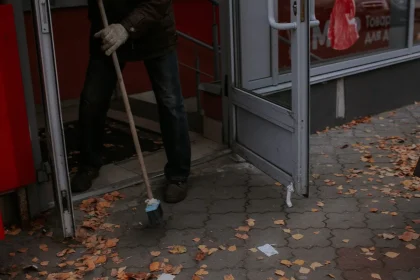 Gloved hand with sanitation cloth cleaning a commercial storefront door