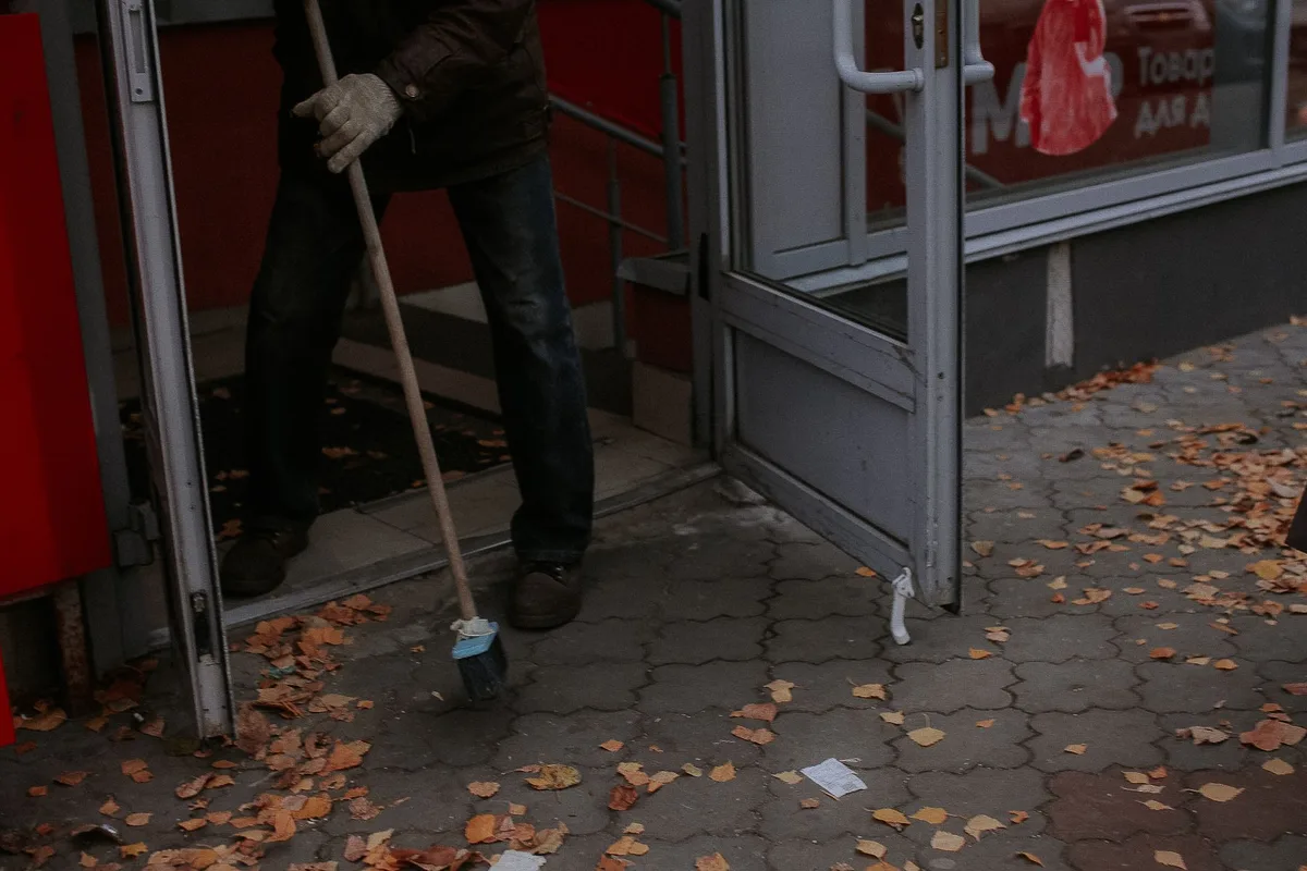 Gloved hand with sanitation cloth cleaning a commercial storefront door