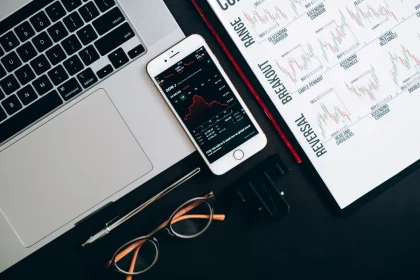 Financial charts and market data displayed on desk with calculator and papers