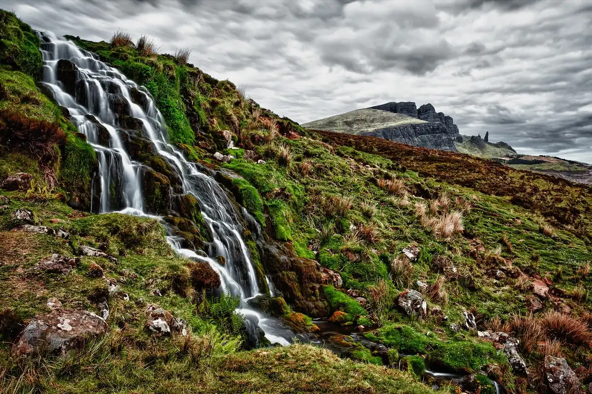 Waterfall cascading into a natural swimming hole surrounded by rocky Arbuckle Mountains landscape and forest