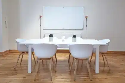 Lightly-lit classroom with empty student desks and an unidentifiable teacher at the whiteboard