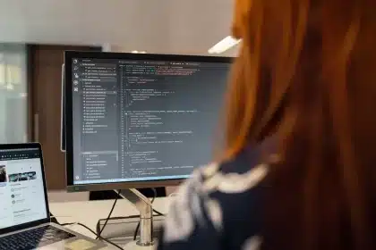 Digital content producer working at a newsroom desk with multiple screens displaying social media and publishing platfor