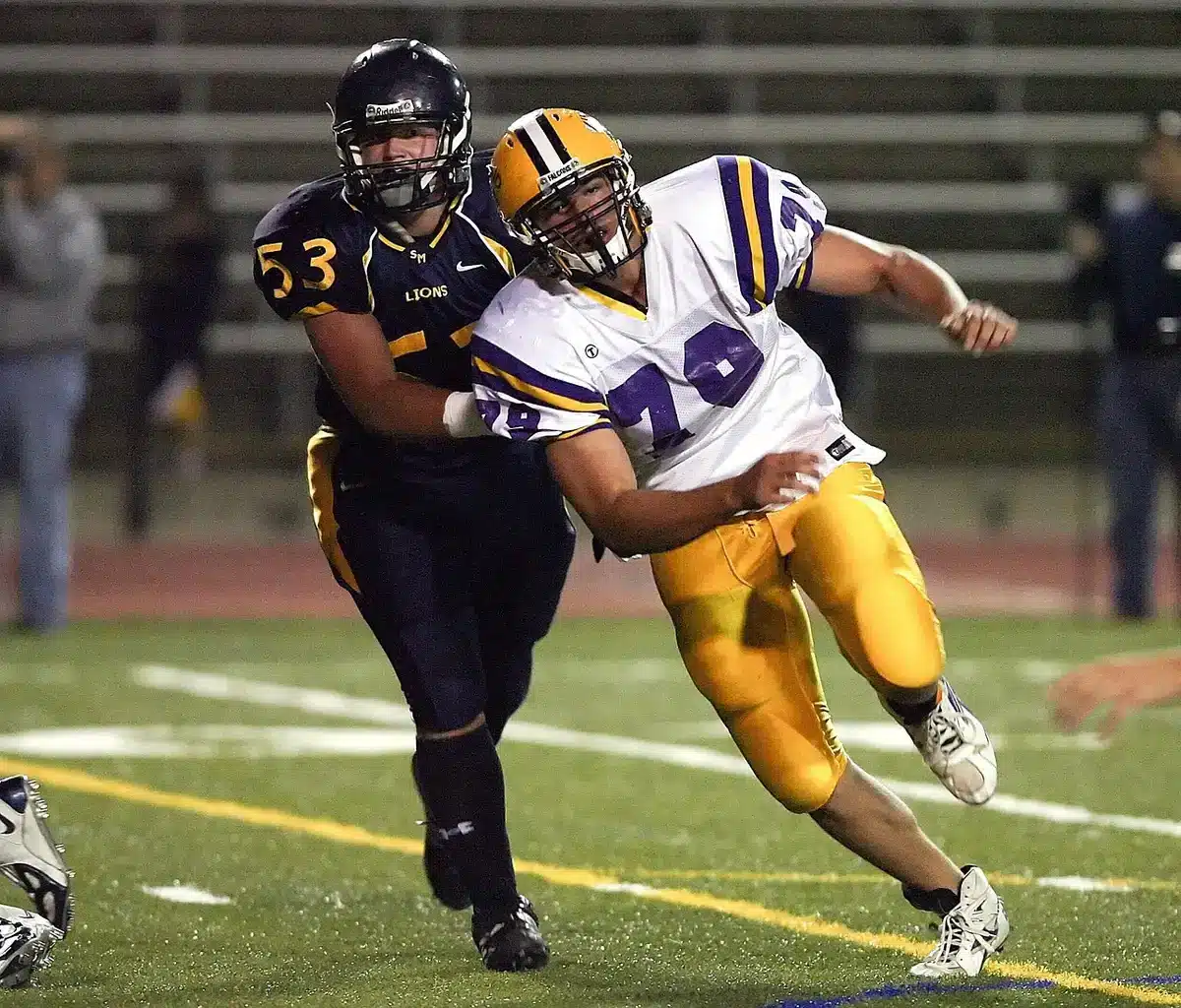 Senior offensive lineman driving a block during a practice drill