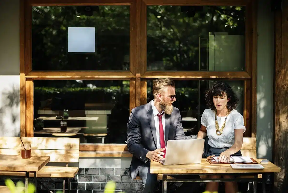 Attendees at a business meeting reviewing documents and plans at a conference table with city skyline in background