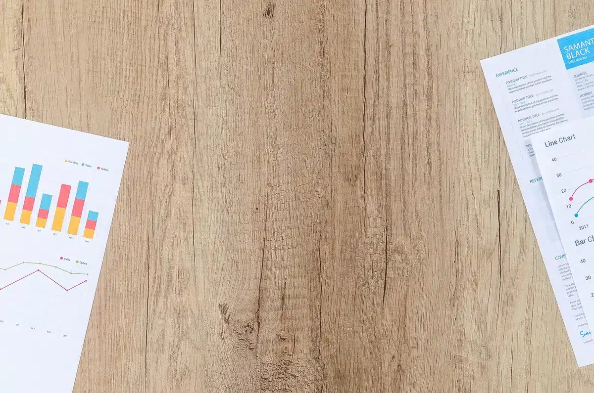 Hands pointing at insurance rate documents on a table by a sunny window