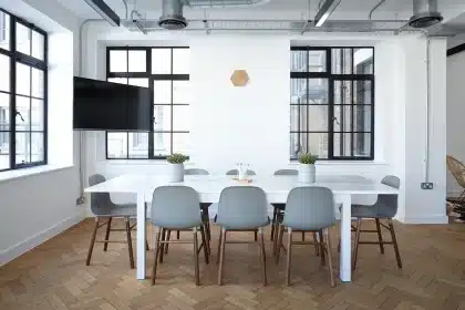 Conference table with printed documents and hands near a window in daylight
