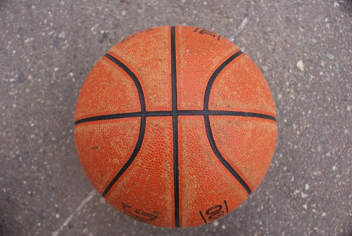 Female basketball player shooting a buzzer-beater with crowd in background during a close game