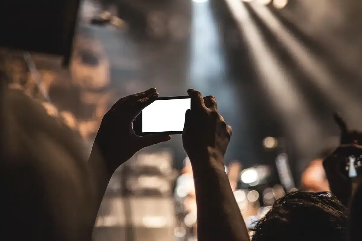 Close-up of hands holding a smartphone taking a photo of a plant in daylight