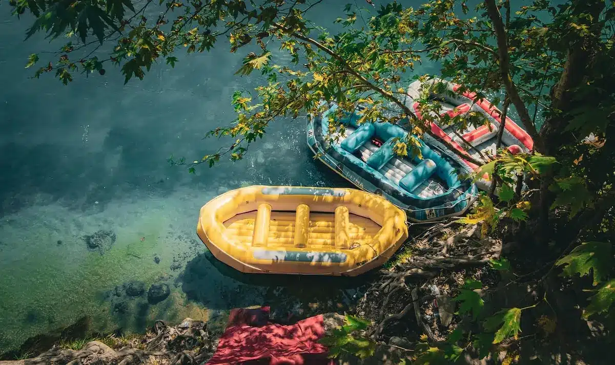 Small boat on a shore with a person rinsing equipment to prevent invasive species spread