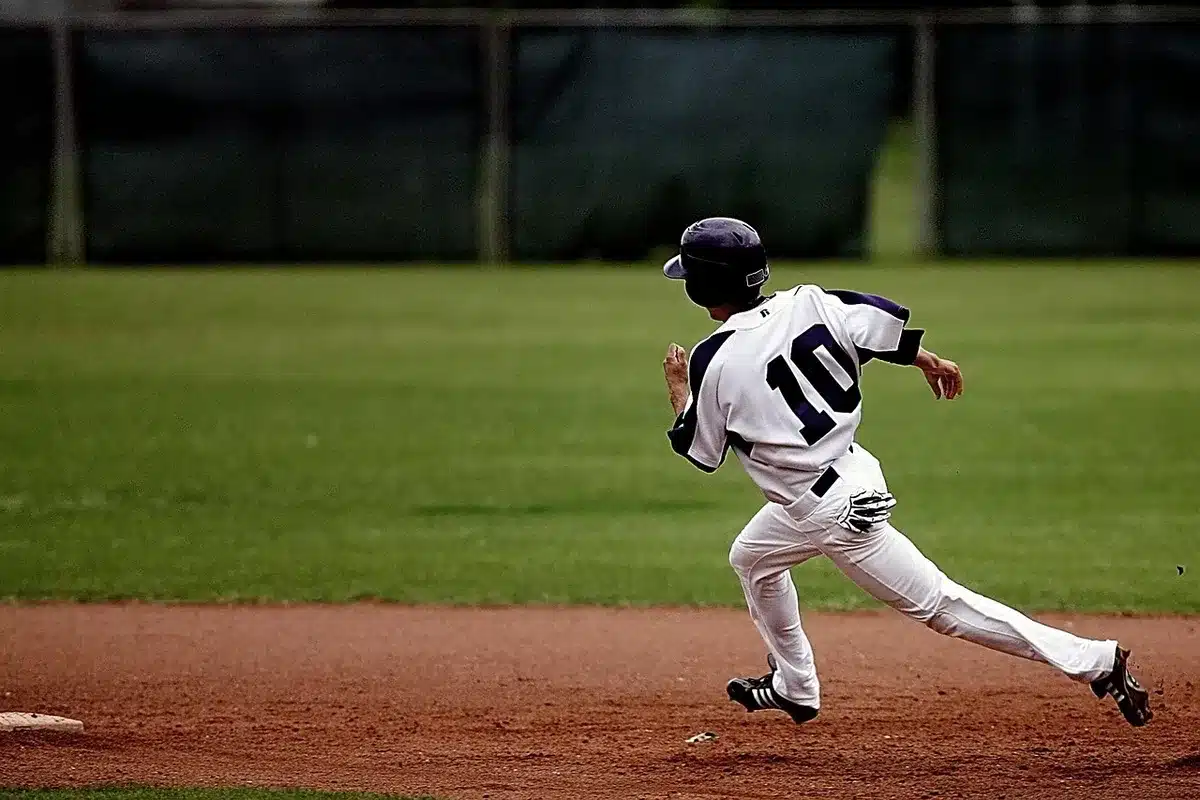 High school player preparing to bat with helmet and bat on a sunny field