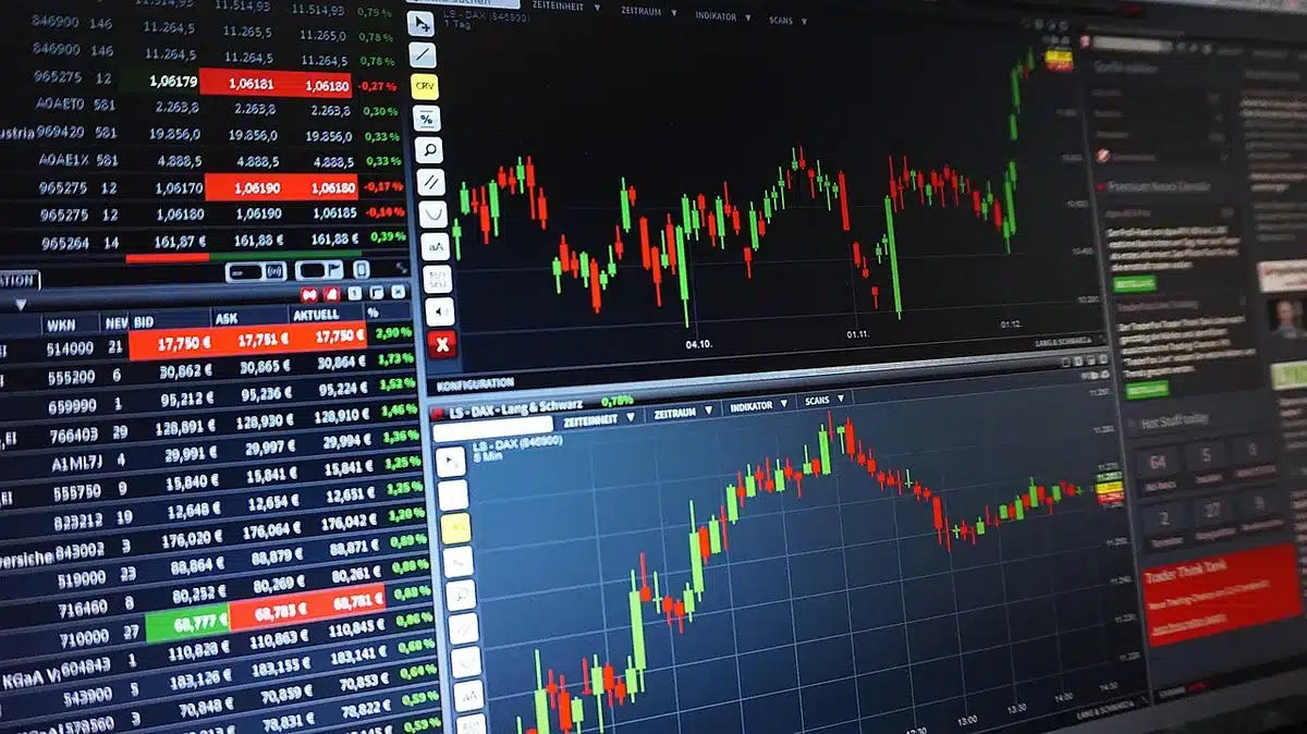Laptop screen showing falling stock charts with a printed earnings summary on a desk