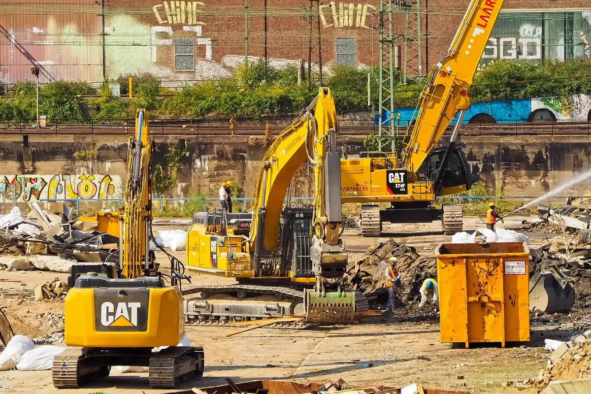 Daytime exterior view of a large stadium construction site with cranes and workers