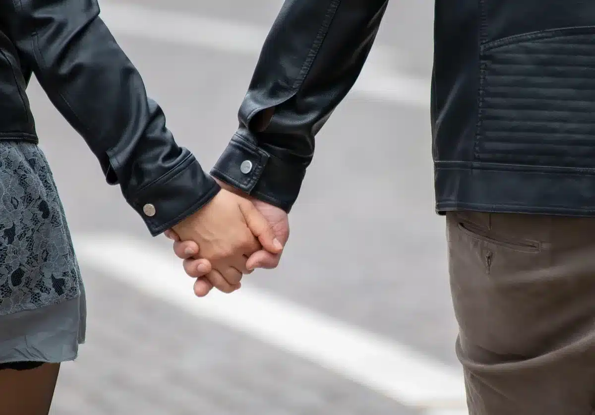 People walking in a park wearing light jackets on a sunny day